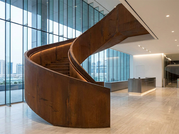 Escalier hélicoïdal sculptural en acier patiné dans un hall intérieur