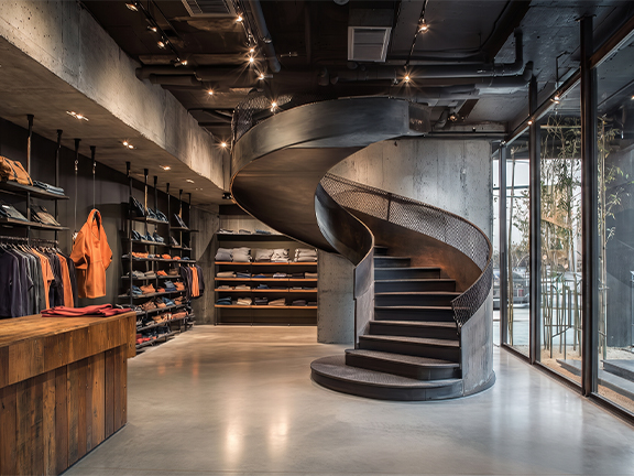 Escalier hélicoïdal métallique industriel avec garde-corps perforé dans un showroom