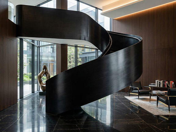Escalier hélicoïdal sculptural noir sur mesure dans un lobby d’hôtel
