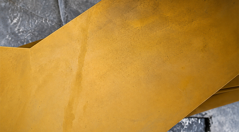 Détail d’une finition métallique patinée dorée pour escalier hélicoïdal sur mesure