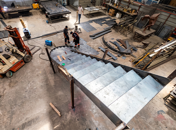 Soudure et ajustement d'un escalier hélicoïdal métallique en cours d'installation sur chantier