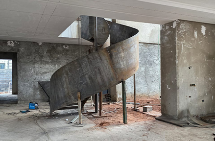 Structure d'escalier hélicoïdal en acier brut en cours d'installation sur chantier